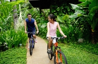 Couple cycling on a path through a park - Asia Images Group
