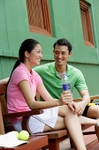 Couple sitting on bench, smiling - Asia Images Group