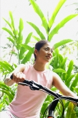 Girl riding a bike through a park - Asia Images Group