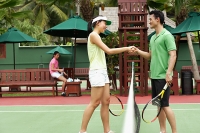 Man and woman shaking hands across tennis court - Asia Images Group