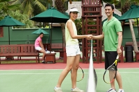 Man and woman shaking hands, looking at camera, tennis match - Asia Images Group