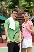 Man and women standing on tennis court, smiling at camera - Asia Images Group
