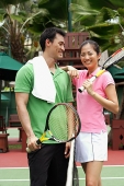 Man and women standing on tennis court with tennis rackets - Asia Images Group