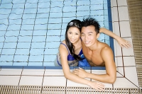 Couple in swimming pool corner, looking up at camera - Asia Images Group