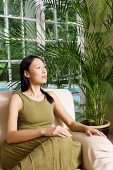 Woman on arm chair, looking away - Asia Images Group