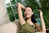 Woman on arm chair, hand behind head - Asia Images Group