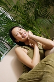 Woman on arm chair, hand on chin, smiling - Asia Images Group
