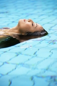 Woman floating in swimming pool - Asia Images Group