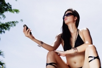 Woman in bikini, holding mobile phone - Asia Images Group