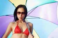 Woman in bikini and sunglasses, holding multi-coloured umbrella - Asia Images Group