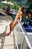 Man in swimming trunks, leaning on railing, eyes closed - Asia Images Group