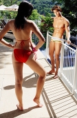Couple in swimwear, woman standing in front of man, hand on hip - Asia Images Group