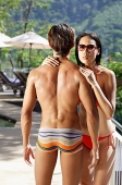 Couple standing face to face, woman looking over shoulder of man - Asia Images Group