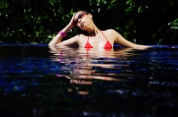 Woman sitting in swimming pool, hand on head - Asia Images Group