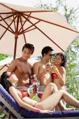 Young adults in swimwear, standing with drinks - Asia Images Group