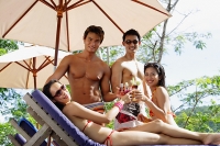 Young adults in swimwear, toasting with drinks - Asia Images Group