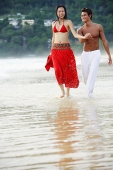 Couple running along beach, ankle deep in water - Asia Images Group