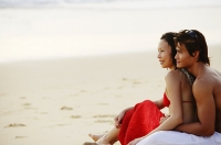Couple sitting on beach, embracing,  looking at sea - Asia Images Group