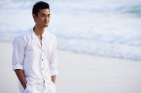 Man standing on beach, hands in pocket - Asia Images Group