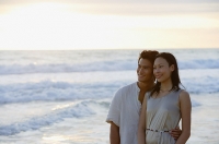 Couple standing on beach, looking away - Asia Images Group