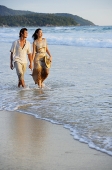 Couple walking on beach, looking away - Asia Images Group