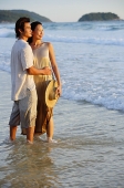 Couple standing on beach, ankle deep in water - Asia Images Group