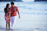 Couple walking on beach, ankle deep in water, holding hands - Asia Images Group