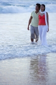 Couple walking on beach, ankle deep in water - Asia Images Group