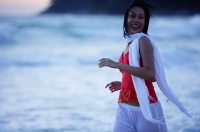 Woman in red top and white scarf, running along beach, smiling - Asia Images Group