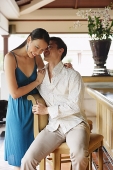 Couple next to bar counter, man whispering in womans ear - Asia Images Group