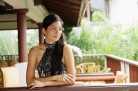 Woman wearing halter top, leaning on railing, arms crossed - Asia Images Group