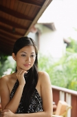 Woman wearing halter top, hand on chin, looking away - Asia Images Group