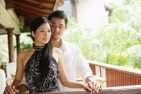 Couple standing together next to railing, man behind woman - Asia Images Group