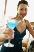 Woman sitting at bar counter, holding cocktail, smiling - Asia Images Group