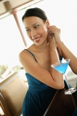 Woman sitting at bar counter, looking away, smiling - Asia Images Group