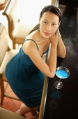 Woman sitting at bar counter, looking up at camera - Asia Images Group