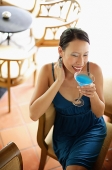 Woman sitting on chair, drinking cocktail, high angle view - Asia Images Group
