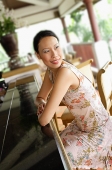 Woman sitting at bar, leaning on counter, looking over shoulder - Asia Images Group