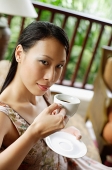 Woman holding cup and saucer, looking at camera - Asia Images Group