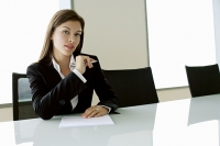 Businesswoman sitting at table, holding pen, looking at camera - Asia Images Group