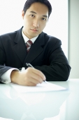Businessman with pen and paper, looking at camera - Asia Images Group