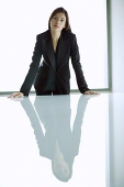 Businesswoman standing with hands on table, looking at camera - Asia Images Group