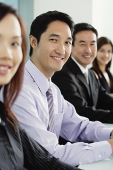 Business people sitting in a row, smiling at camera - Asia Images Group
