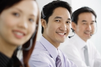 Executives wearing headsets, smiling at camera - Asia Images Group