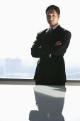 Businessman standing with arms crossed, looking at camera - Asia Images Group
