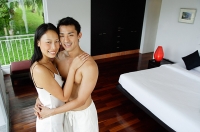 Couple embracing in bedroom, looking at camera - Asia Images Group