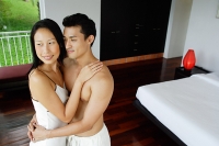 Couple embracing in bedroom, looking away - Asia Images Group