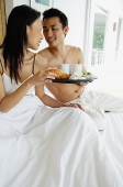 Couple having breakfast in bed, man holding tray - Asia Images Group