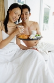 Couple having breakfast in bed, smiling at camera - Asia Images Group