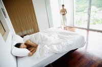 Woman in bedroom, sleeping, man walking in with tray - Asia Images Group